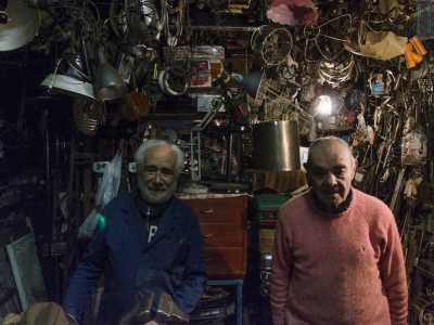 I fratelli Martinelli nel piccolo spazio di lavoro della bottega, sommersa da oggetti di metallo di ogni foggia